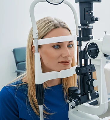 Person seated at a slit-lamp during an eye exam